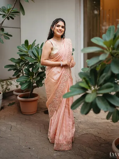 A full-length shot of the peach saree look. The makeup is kept dewy and fresh, complementing the soft color of the outfit.