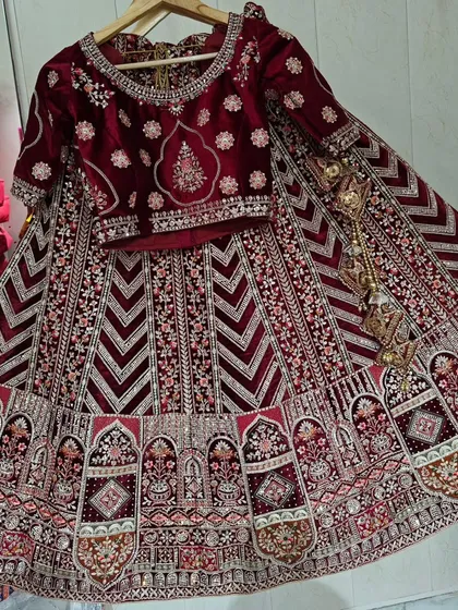 Here is a full set of a maroon velvet bridal lehenga. You can see the detailed embroidery on the blouse and the heavy work on the skirt, promising a truly grand appearance.