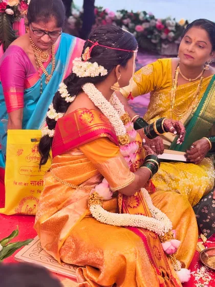 A candid moment from a wedding ceremony, showing the bride's beautiful braided hairstyle adorned with fresh flowers, a signature element of a traditional Maharashtrian look.