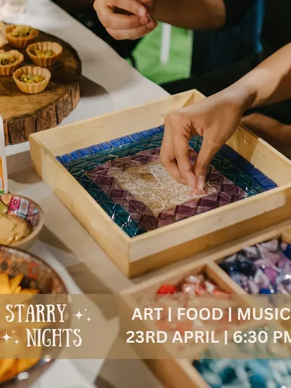 Our Starry Nights aren't just about art; they're a feast for the senses. Here, a guest is creating a beautiful mosaic tray while enjoying some of the delicious food we have on offer. Art, food, and music make for the perfect night.
