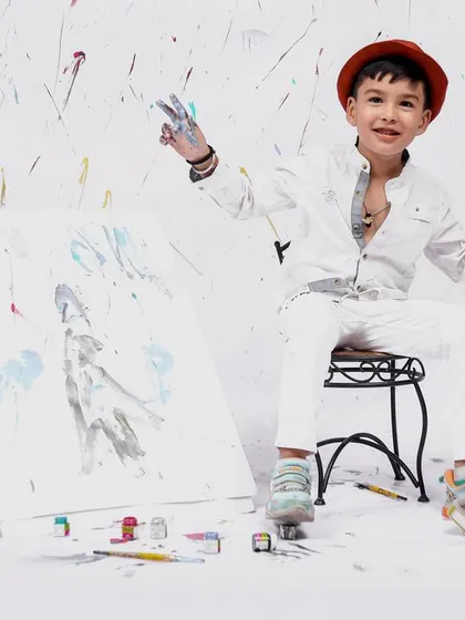 A candid moment from our painter-themed session, where the little artist is proudly showing off his colorful hands after a fun time painting.