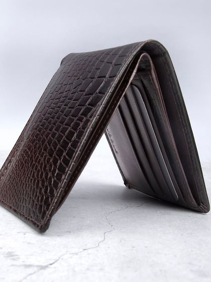 A standing shot of a dark brown crocodile-textured wallet.