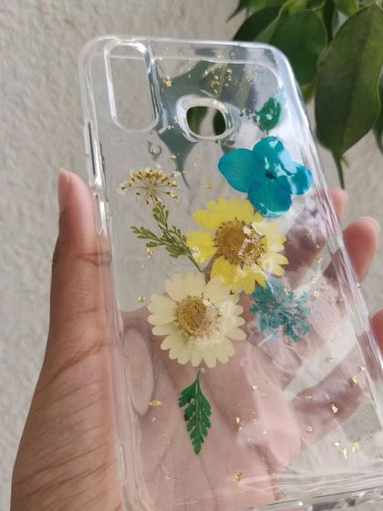 A custom phone case made with real dried flowers. I arranged these yellow and blue daisies and added a sprinkle of gold leaf to create a beautiful, botanical design.