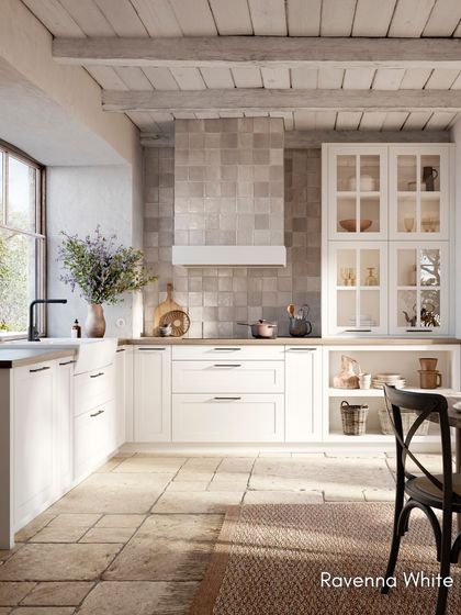 A full view of the RAVENNA White kitchen, showcasing its harmonious blend of white surfaces, natural wood countertops, and rustic stone flooring.