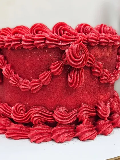 A vibrant, glittering red vintage buttercream cake. The intricate piping and sparkling finish make it a true showstopper.