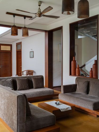 The formal living area features low-slung sofas and earthy tones, creating a comfortable and grounded space for conversation.