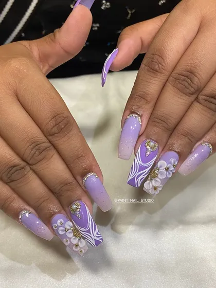 Festive bling for Diwali 2024. This elaborate set features long, coffin-shaped nails with a purple ombré, intricate white line work, 3D flowers, and plenty of crystals.