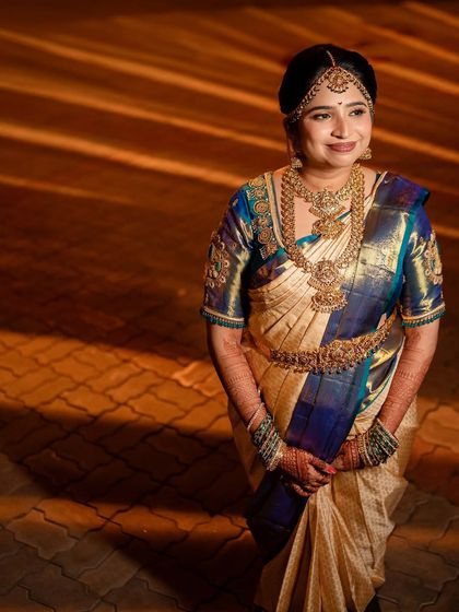 This bride's look is all about classic elegance. The makeup is subtle yet defining, paired with a traditional blue and gold Kanjivaram saree and magnificent temple jewellery for a truly regal appearance.