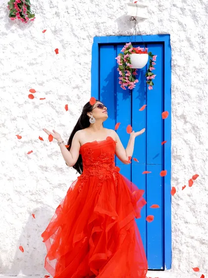 A joyful moment of a woman in a stunning red gown, surrounded by falling petals. This captures a sense of freedom and celebration.