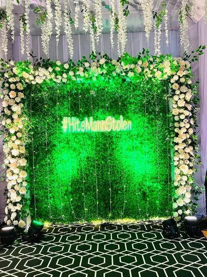 This lush green foliage wall with a custom neon hashtag is a classic and popular choice for a Sangeet or reception photo booth. The hanging fairy lights and wisteria add a touch of magic.