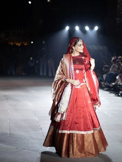 A wide shot of Kriti Sanon walking the ramp in Varanasi, showing the scale of the event and the audience.