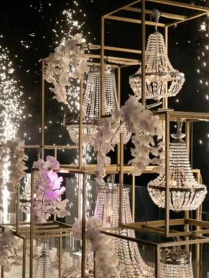 A spectacular display of stacked chandeliers adorned with white orchids, with cold pyro effects creating a moment of high drama.