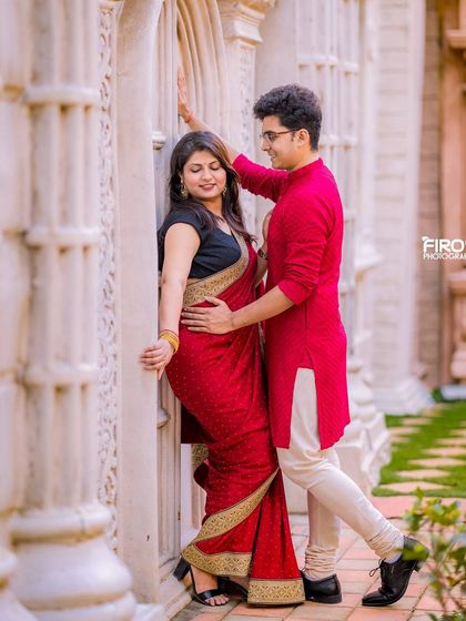An intimate moment for a couple in traditional red attire against a wall of white pillars.