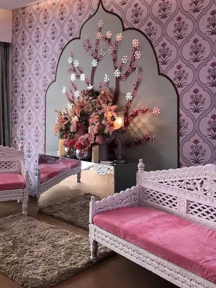 This symmetrical seating arrangement with carved white benches and a stunning floral art piece creates a sense of balance and royal elegance for an indoor Mehendi.
