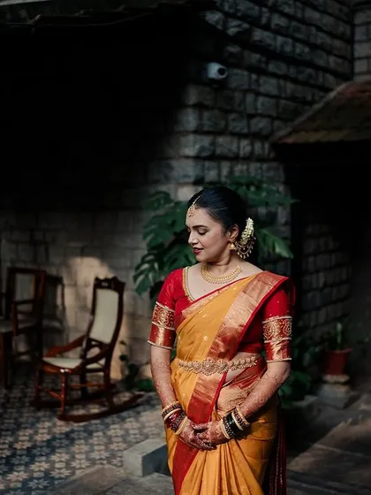A bride in a yellow and red saree, captured in a moment of quiet contemplation against the backdrop of our heritage architecture.