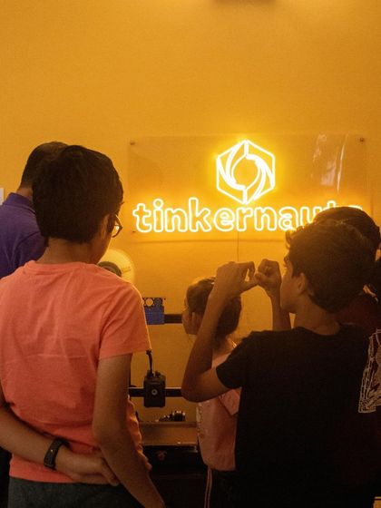 A group of students watches a 3D printer with fascination. There's a real sense of wonder in seeing a digital file become a tangible object right before your eyes.