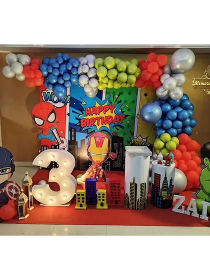 An action-packed Avengers theme party for a 3rd birthday. This decoration includes cutouts of Captain America, Iron Man, Spider-Man, and the Hulk, with a comic-book style backdrop and a large light-up number '3'.