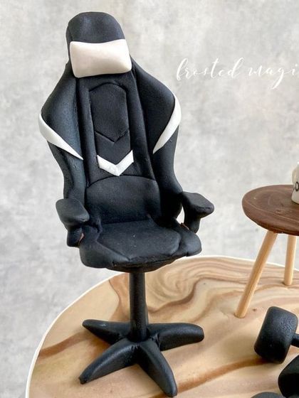 This cake topper combines a love for gaming and fitness. The miniature gaming chair and dumbbells are all hand-sculpted from fondant.