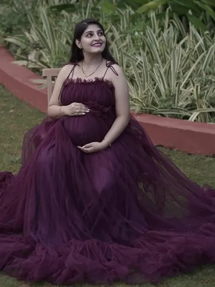 A joyful solo shot of a mom-to-be in our purple tulle gown. The full skirt spreads out on the lawn, creating a beautiful, regal look.