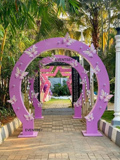A grand entrance for a fairy party, featuring layered purple arches adorned with delicate butterflies.