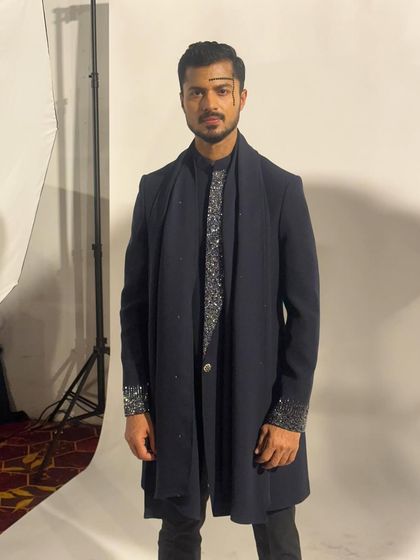 A studio-style shot taken backstage, showing the sharp silhouette of the designer's creation against a white background.