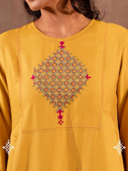 A detailed view of the Pakka hand embroidery on our Ruhani Yellow Pleated Kurta. Each stitch is counted and placed by hand, creating a resilient and sacred motif that carries the history of desert artisans.