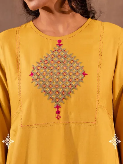 A detailed view of the Pakka hand embroidery on our Ruhani Yellow Pleated Kurta. Each stitch is counted and placed by hand, creating a resilient and sacred motif that carries the history of desert artisans.