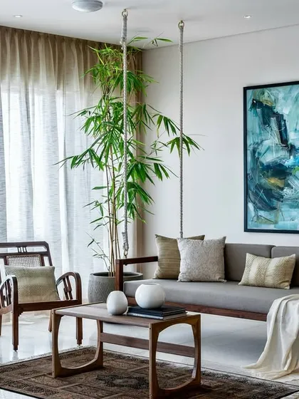 We blend minimalist design with touches of Indian warmth to create homes that are both peaceful and inviting. The traditional wooden swing in this Terrazzo Residence living room adds a sense of playfulness and cultural resonance to the clean, contemporary aesthetic.
