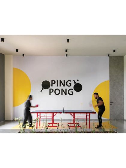 The ping pong area in the 'Meraki' clubhouse is defined by a bold wall graphic, turning a simple game room into a visually engaging space.