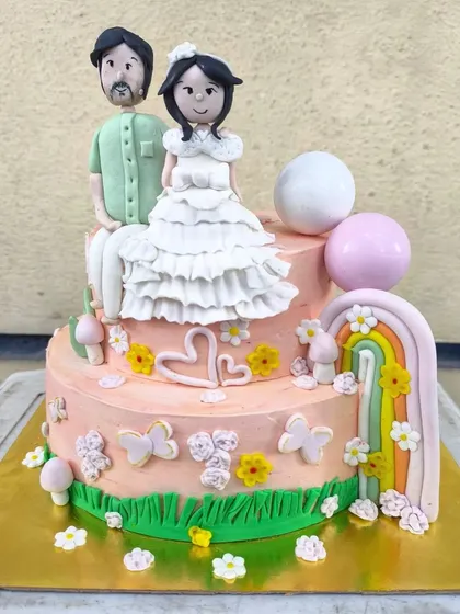 A special cake celebrating a father and daughter together. This two-tier creation features custom fondant figurines, a whimsical rainbow, and lots of cute butterflies and flowers.