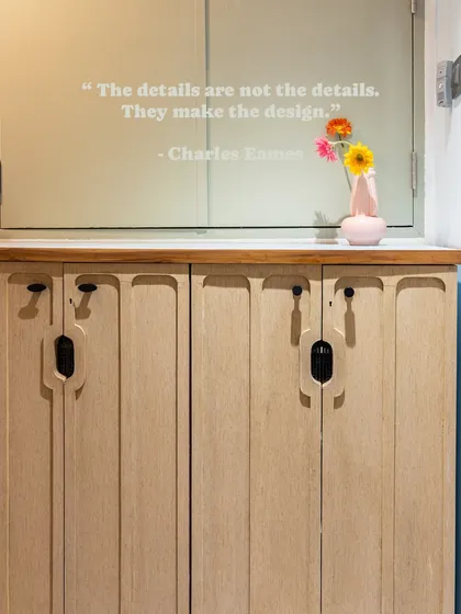 This entryway shoe rack is designed with slim, grooved doors and a marble top, providing essential storage while maintaining a sleek and modern look. The quote from Charles Eames reminds us that details make the design.