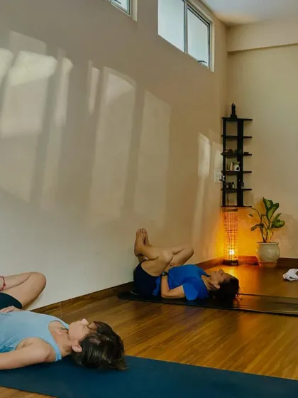 Students resting in restorative poses like Supta Baddha Konasana (reclining bound angle) and Viparita Karani (legs up the wall), promoting deep relaxation.