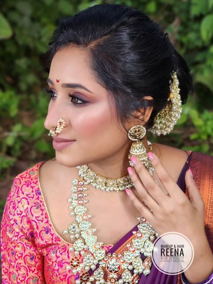 A side profile showcasing the elegant messy bun with pearl accessories and the classic Maharashtrian nath.