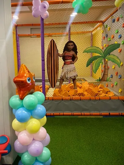 A Moana cutout stands ready with her surfboard in the foam pit, perfectly matching the "Surf's Up" theme.