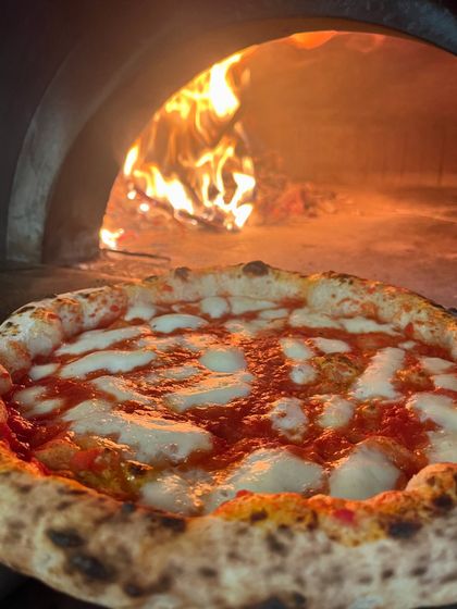A Margherita basking in the glow of the wood fire. You can almost smell the bubbling cheese and toasting crust.