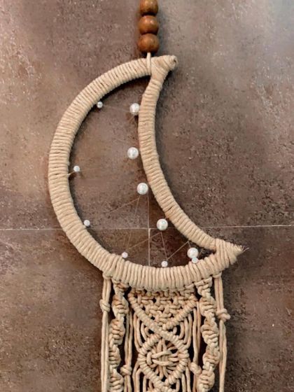 A close-up of the top of the moon dreamcatcher, highlighting the wrapped crescent shape and the beaded web.