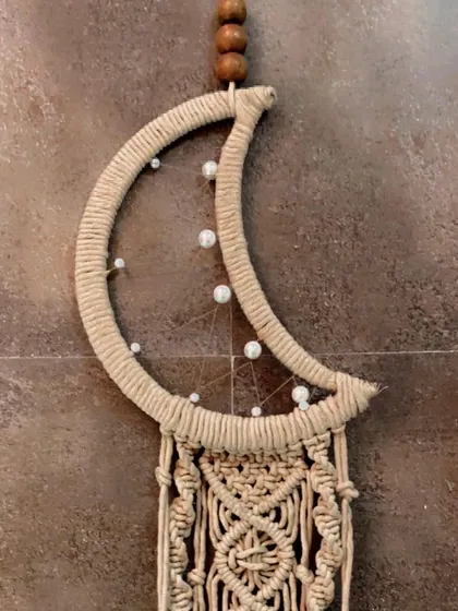 A close-up of the top of the moon dreamcatcher, highlighting the wrapped crescent shape and the beaded web.