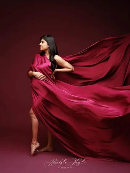 The dynamic movement of this draped red fabric adds a sense of power and artistry to this striking maternity portrait.