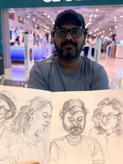My friend Shrikant holding up my sketchbook, with his own caricature looking back at him.