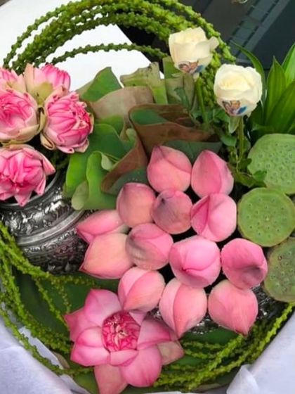 An exquisite offering basket containing fresh pink lotus buds, lotus seed pods, and white roses. This arrangement is perfect as a respectful offering for a pooja or as a beautiful decorative element.