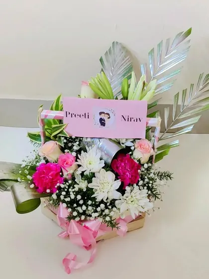 The couple's floral basket shown from the side, highlighting the decorative silver leaves and the soft pink ribbon that ties the look together.