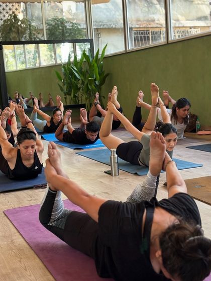 A class works on their backbends together in bow pose, building strength in the back and opening the chest and shoulders.