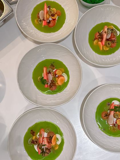 A vibrant cold soup with crab, heirloom tomatoes, and a bright green gazpacho base. This is a refreshing and elegant seafood starter.