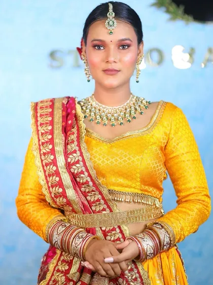 A full portrait of the bride in her colorful lehenga. The makeup is kept bright and fresh, perfect for a daytime wedding or a festive sangeet ceremony.