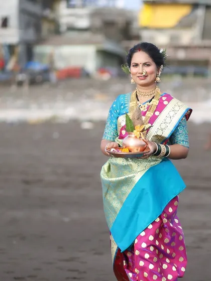 The model is holding a traditional 'puja thali' for Sagar Pujan (worship of the sea), an important ritual during Narali Pournima.