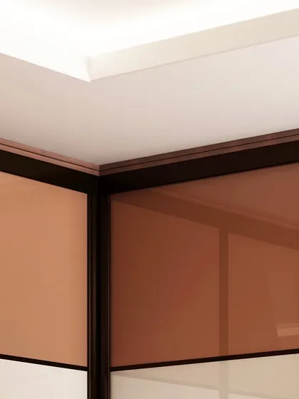 A close-up detail of the top corner of a sliding wardrobe, showing the clean lines and precision fit of the panels and frame against the ceiling.
