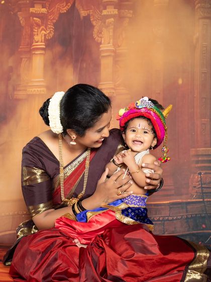 A mother and her baby, dressed as little Krishna, share a loving gaze during their themed photoshoot.