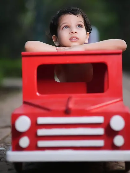 Daydreaming in his little red truck. This simple outdoor prop is great for capturing a child's thoughtful and curious expressions.