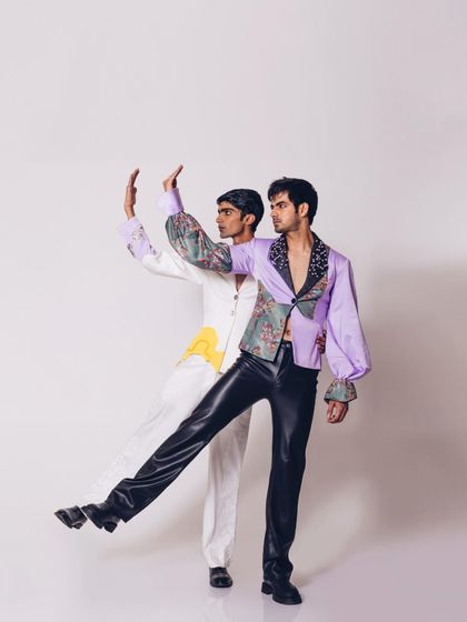 A duplicate of image 51, this shot for the "Monsieur" collection highlights the playful interaction between the models. The styling combines classic tailoring with bold prints and unconventional materials like faux leather.