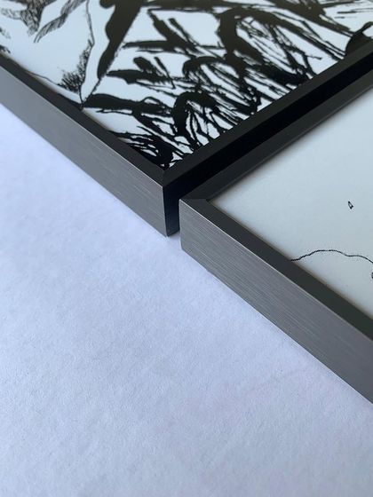 A close-up of the corner of our gray metal floater frames used for manga panels. The brushed metal finish adds a touch of sophistication to the black and white artwork.